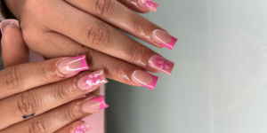 Pink French tip nail art with glossy nude polish and delicate white floral designs on long square-shaped nails.