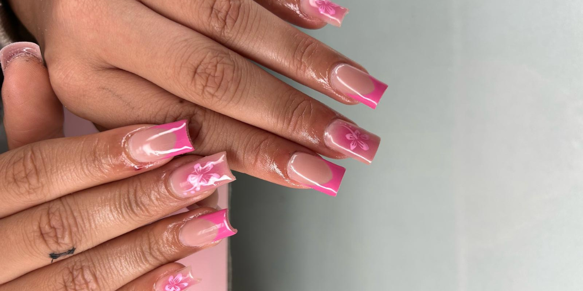 Pink French tip nail art with glossy nude polish and delicate white floral designs on long square-shaped nails.