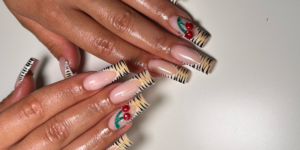 Long nude square nails with black-and-white animal print tips and cherry accents.