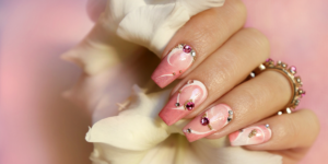 Pink acrylic nails with rhinestone accents.