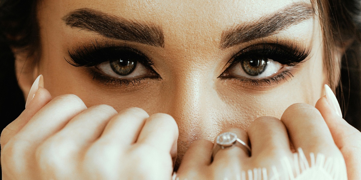 Close-up of a woman's face highlighting beautifully shaped eyebrows, long eyelash extensions, and flawless eye makeup after a professional beauty treatment.